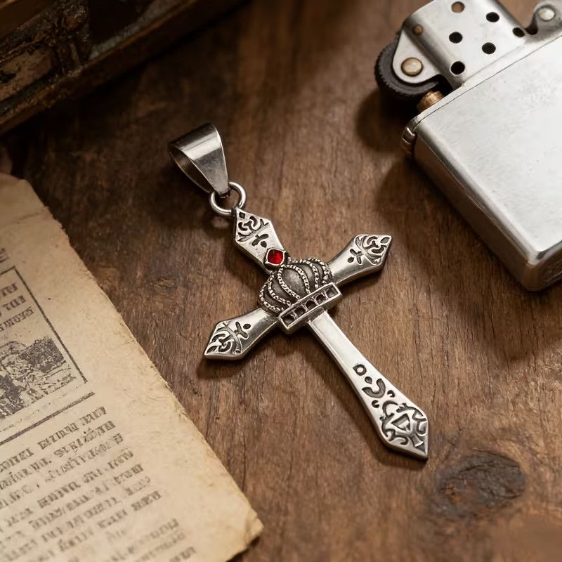 Vintage gothic crown cross pendant with red crystal detail on wooden background