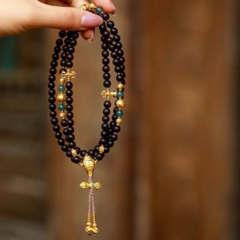 Woman wearing 108 natural agarwood mala necklace with ancient sand gold pendant