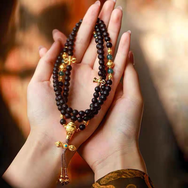 Woman wearing 108 natural agarwood mala necklace with ancient sand gold pendant