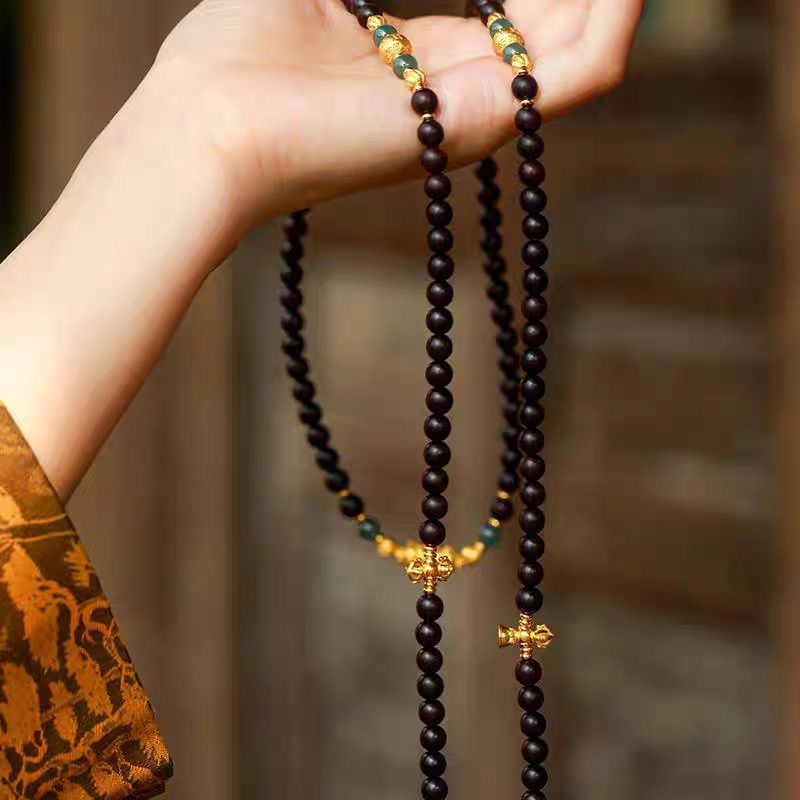 Woman wearing 108 natural agarwood mala necklace with ancient sand gold pendant
