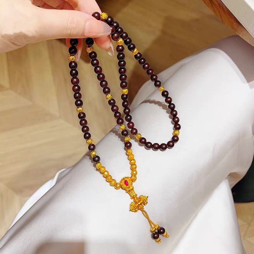 Woman wearing 108 natural agarwood mala necklace with ancient sand gold pendant